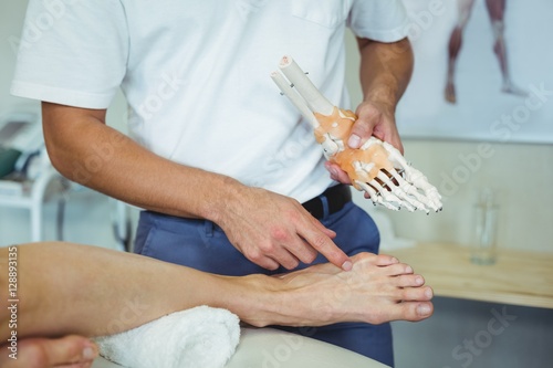 Physiotherapist explaining feet model to patient photo