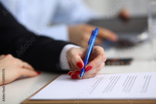 Businesswoman sitting in office, writing on documents