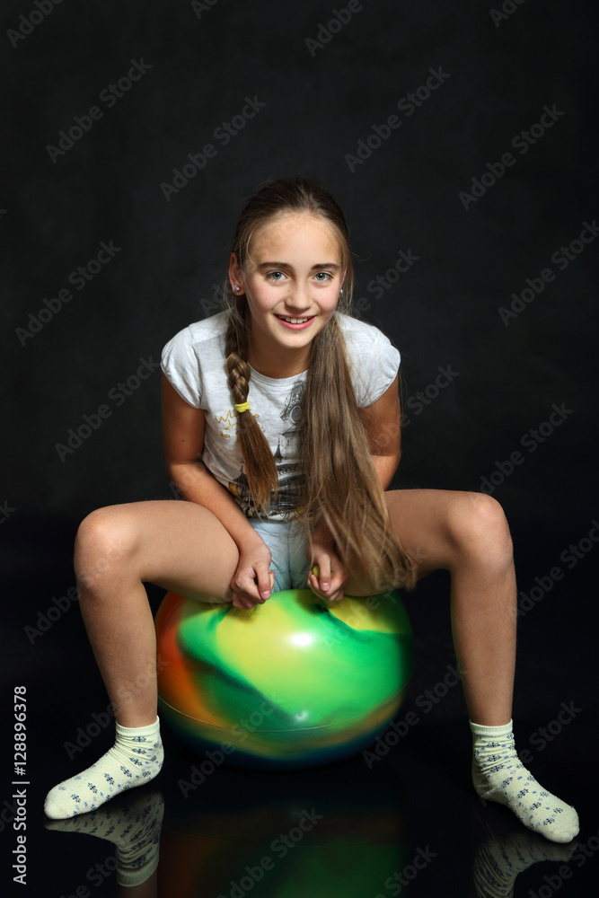 Obraz premium Śliczna dziewczynka, nastolatka siedzi na piłce z uszami.