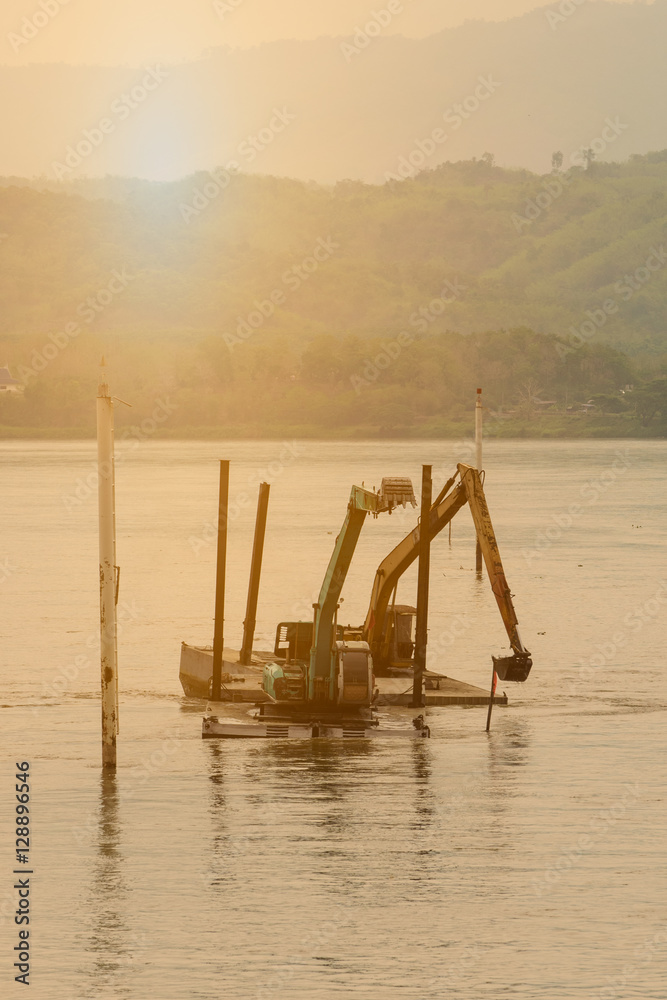 Two shovel buckets on pontoon are digging mud ,sand and bese ro Two shovel buckets on pontoon are digging mud ,sand and bese ro