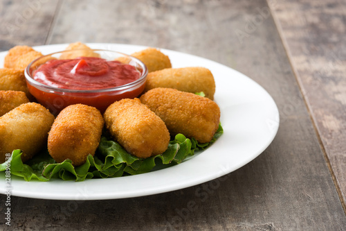 Traditional fried Spanish croquetas (croquettes) with ketchup in plate on wooden background
