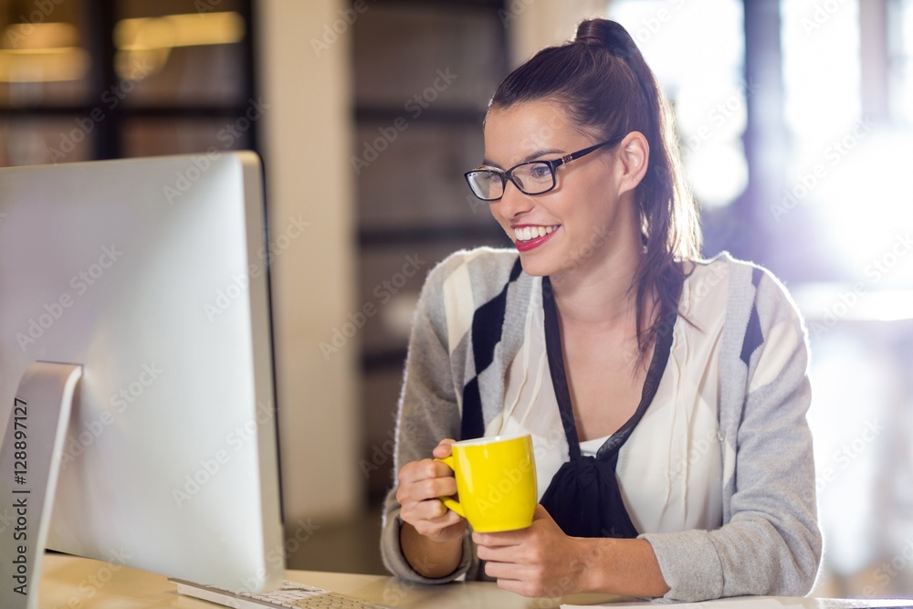 Smiling woman holding coffee cup in office Smiling woman holding coffee cup in office