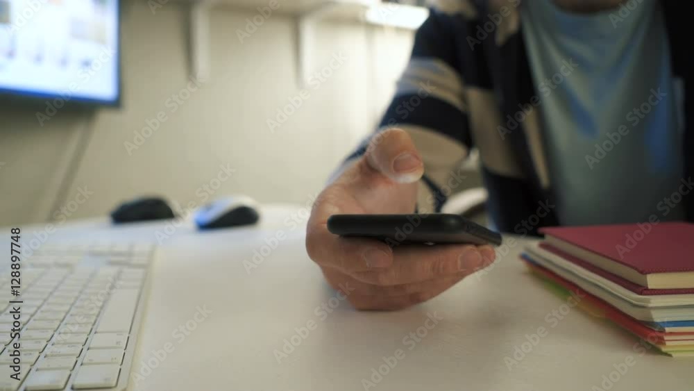 Businessman using modern smartphone while working at his office workplace. Close up dolly shot of man's hands using smartphone. Businessman using modern smartphone while working at his office workplace. Close up dolly shot of man's hands using smartphone.