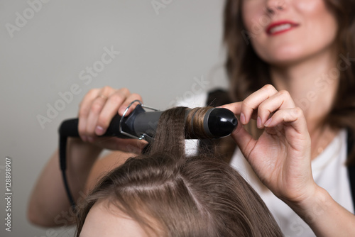 Cropped image, the process of hair curling. Hairdresser and client. Closeup