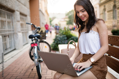 Woman using laptop in city © NDABCREATIVITY
