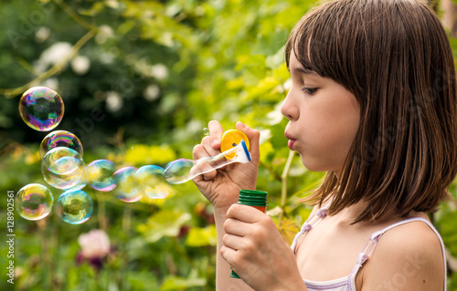 Little girl inflates soap bubbles in the garden