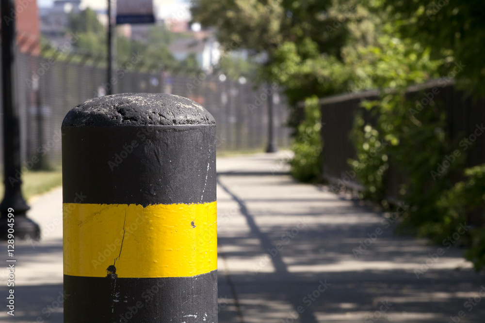 Barrier blocking a walking path. Cement post with yellow stripe. Barrier blocking a walking path. Cement post with yellow stripe.