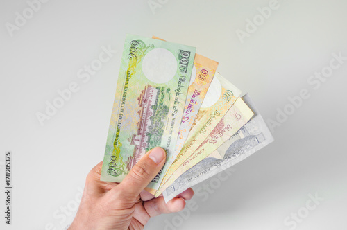 Man holding a bunch of Bhutanese Ngultrum banknotes in his hand