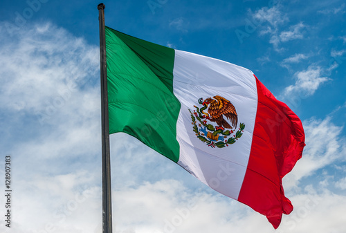 Flag of Mexico over blue cloudy sky