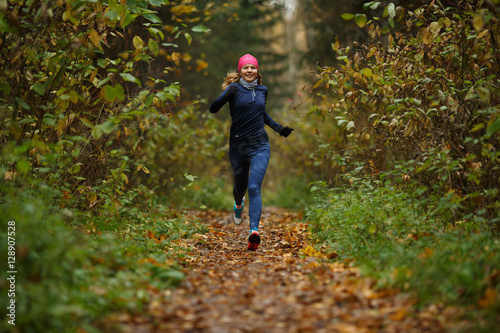 Young sportswoman running among trees