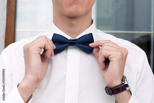 the man corrects bow-tie on a neck. Morning of the groom. Accessory of men's wear