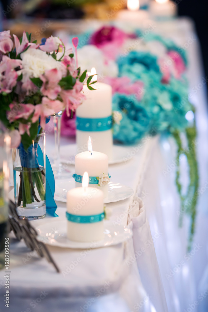 decoration of a wedding table of the groom and bride. Flowers of blue color and candles decoration of a wedding table of the groom and bride. Flowers of blue color and candles