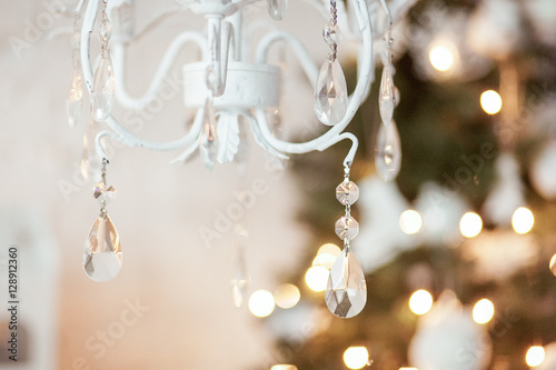 elegant chandelier in the background Christmas decorations, garlands, xmas tree. interior in white and gold colors