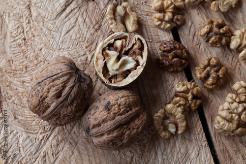 Walnut kernels and whole walnuts on old wooden table, selective