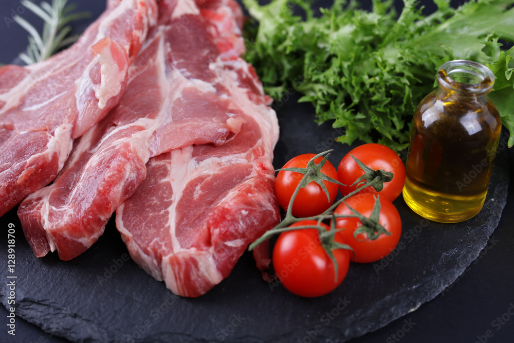 Raw pork neck meat on black background, spices, vegetables, olive oil. Cooking background, healthy eating concept. Raw pork neck meat on black background, spices, vegetables, olive oil. Cooking background, healthy eating concept.