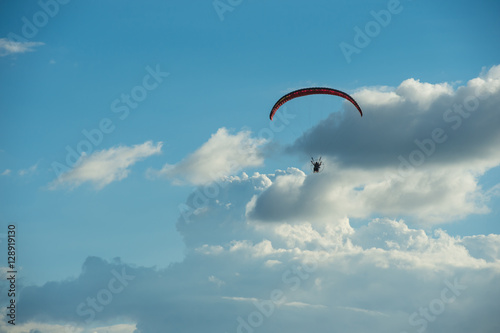 Paramotor flying over the fields in the sky.