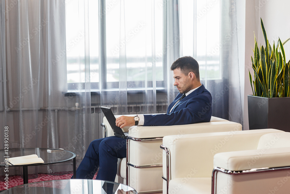 Young businessman working at laptop in lobby