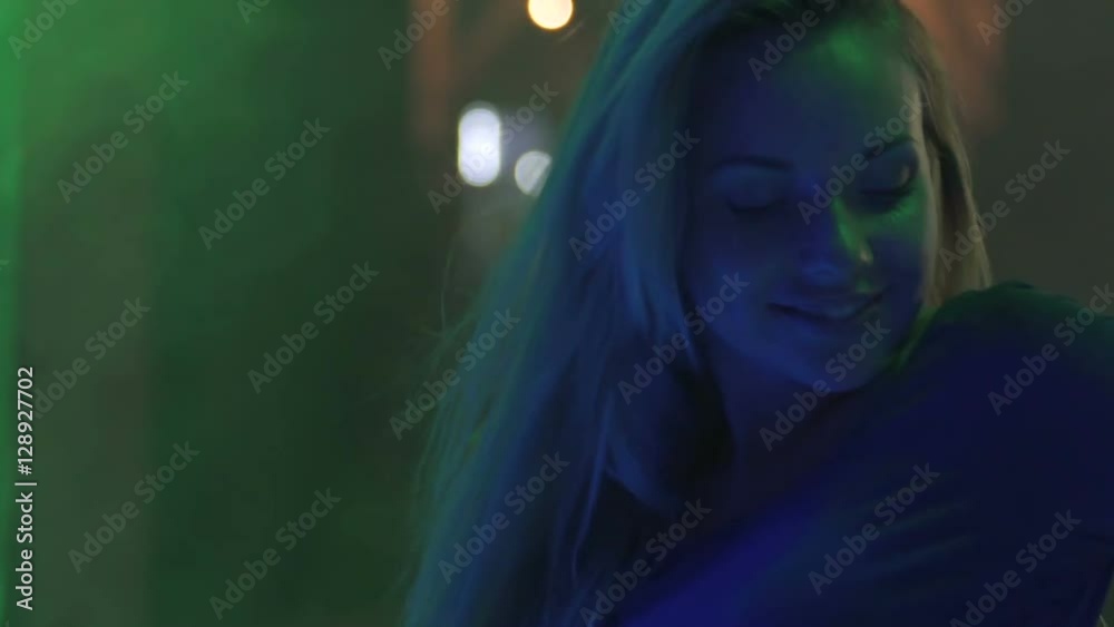 Smiling face of beautiful go-go dancer moving to music in club, smoke and lights Smiling face of beautiful go-go dancer moving to music in club, smoke and lights