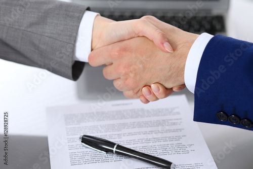 Businessman and business woman shaking hands to each other above signed contract