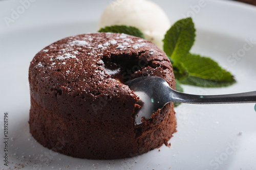 Concept: restaurant menus, healthy eating, homemade, gourmands, gluttony. White plate with chocolate fondant and ice cream on a messy vintage wooden background. photo