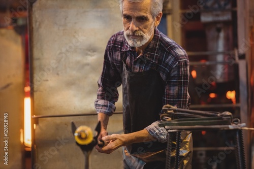 Glassblower shaping a molten glass photo