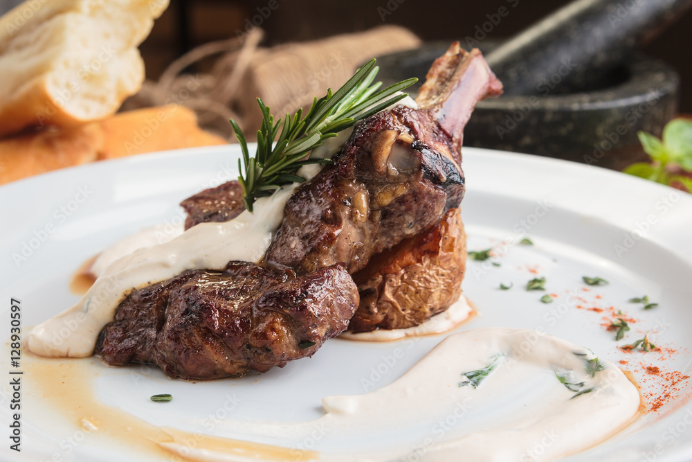 Concept: restaurant menus, healthy eating, homemade, gourmands, gluttony. White plate of lamb rack on wooden table and ingredients on background.