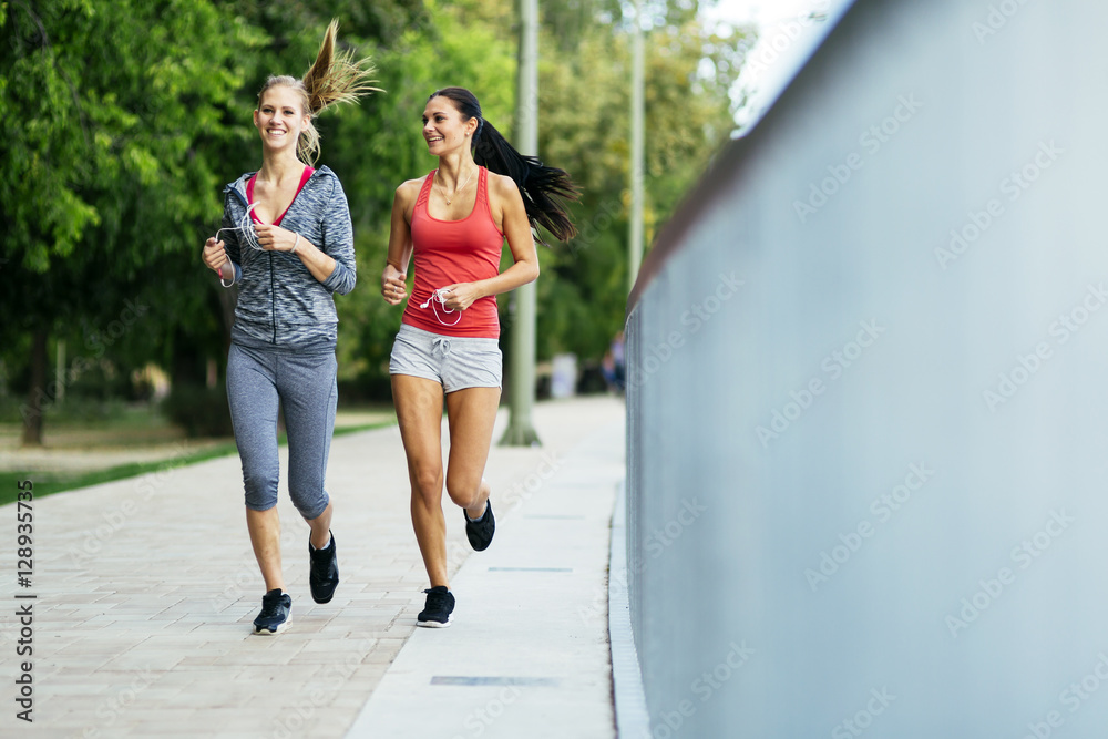 Two sporty women jogging in city