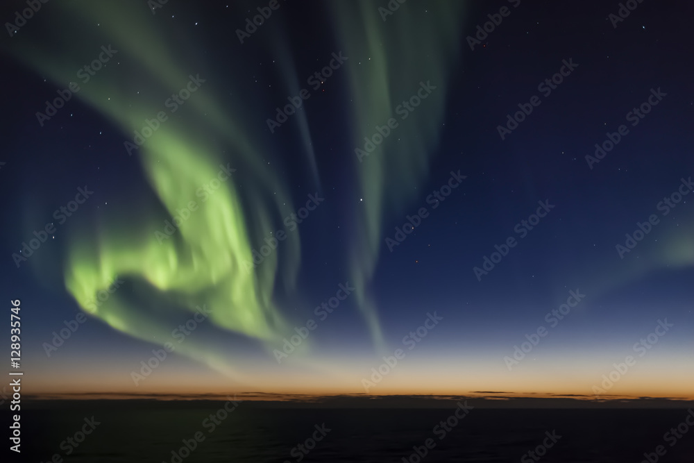 Aurora borealis (Northern Lights) over Arctic Ocean during sunset