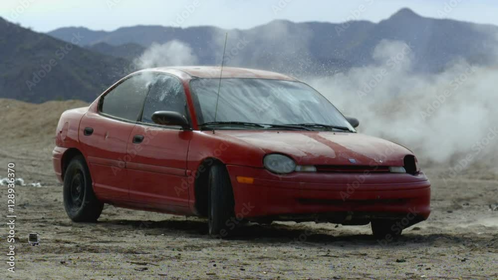 A tight shot of a red car shot up by bullets in slow motion. A tight shot of a red car shot up by bullets in slow motion.