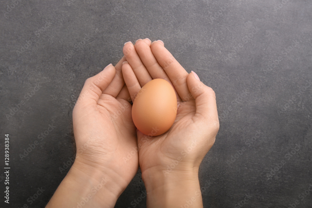 Woman hands holding raw egg on color background Woman hands holding raw egg on color background