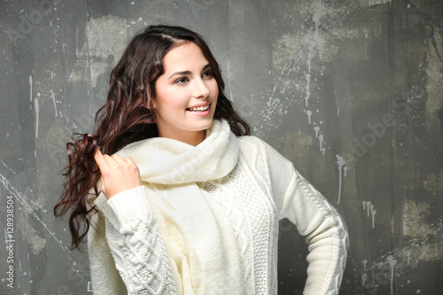 Beautiful young woman in warm sweater on grunge background