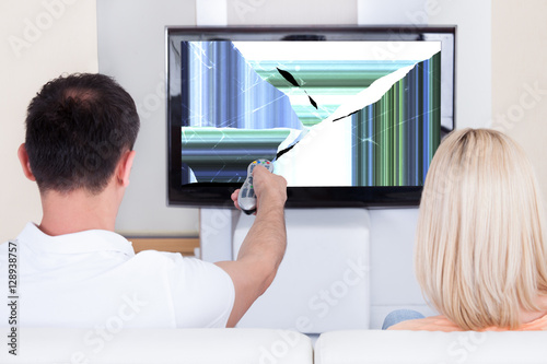 Couple In Front Of Television Showing Distorted Screen