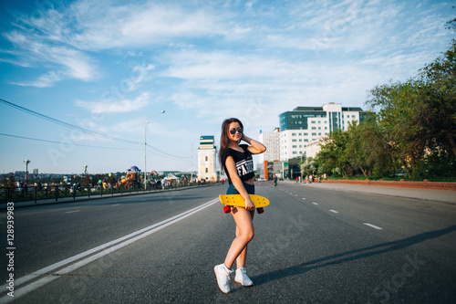 beautiful young girl with skateboard on city streets in the summ