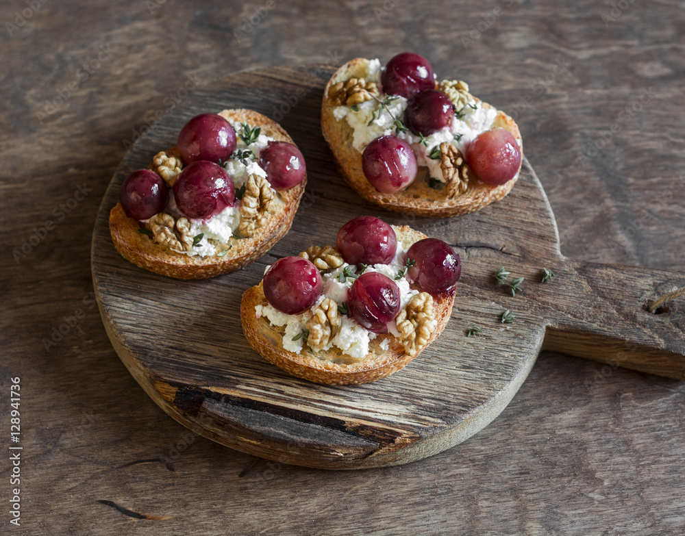 Roasted grape and goat cheese bruschetta on a wooden background