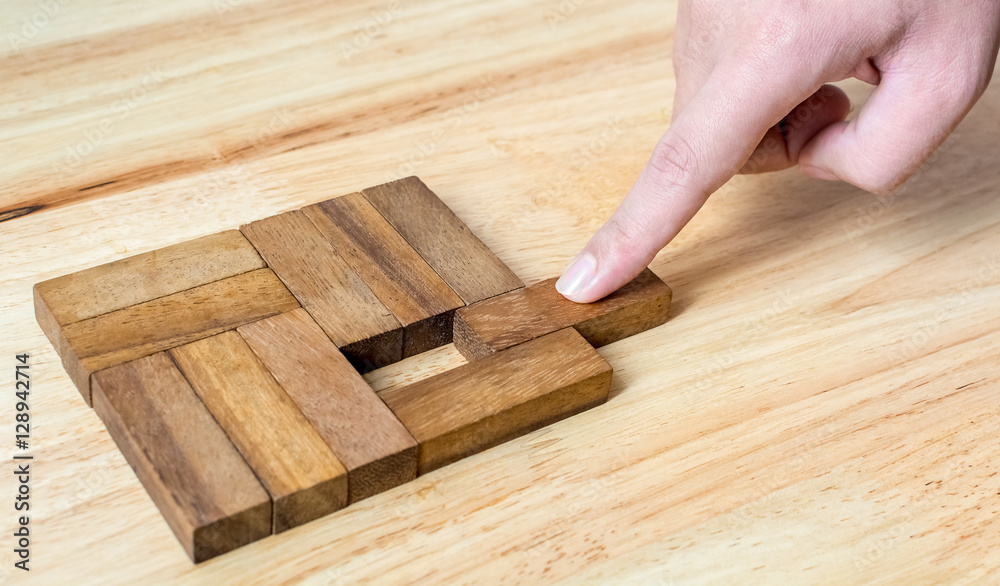 Hand push last piece of wood block to complete the unity, metaphor to key to success. Hand push last piece of wood block to complete the unity, metaphor to key to success.