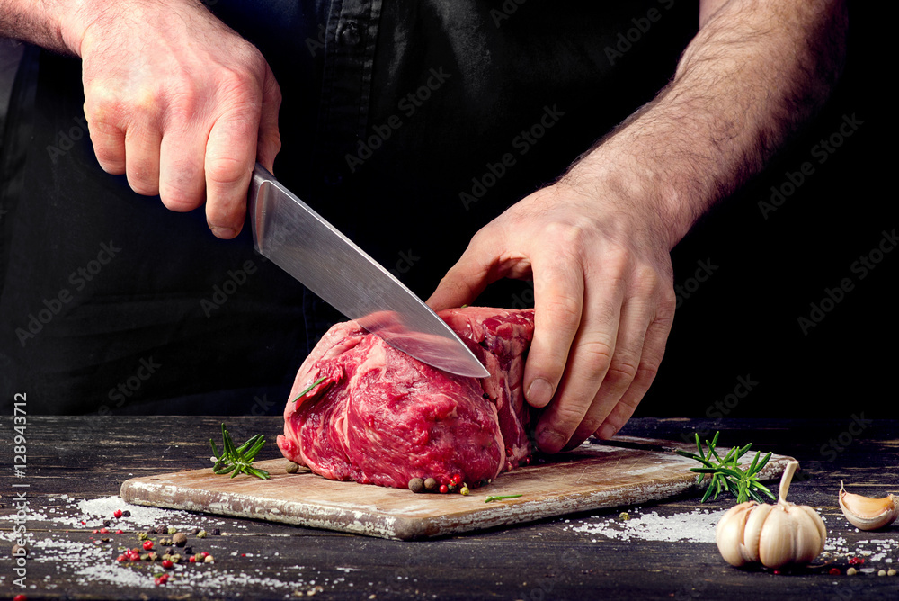 Man cutting raw beef meat - obrazy, fototapety, plakaty 