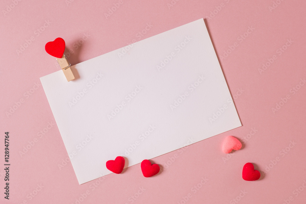Valentine day composition: stationery / photo template with clamp and small hearts on light pink background. Top view. Valentine day composition: stationery / photo template with clamp and small hearts on light pink background. Top view.