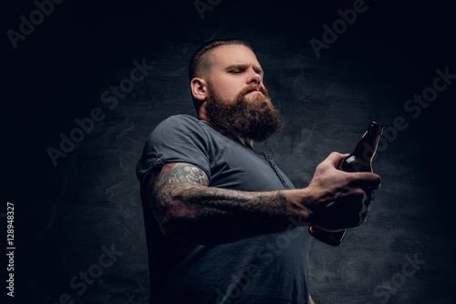 Bearded man holds the beer bottle.