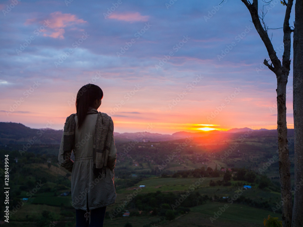 Young woman watching sunrise high in the mountain