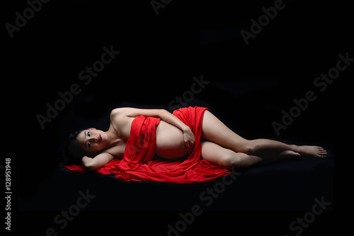 Pregnant asian woman laying down on red scarf