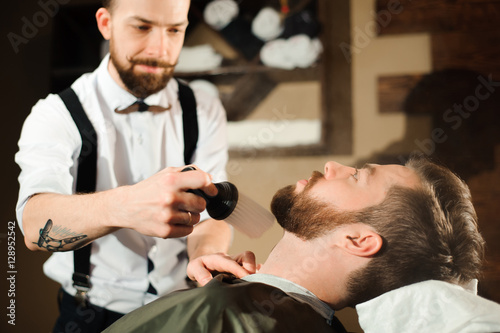 Master cuts hair and beard of men in the barbershop