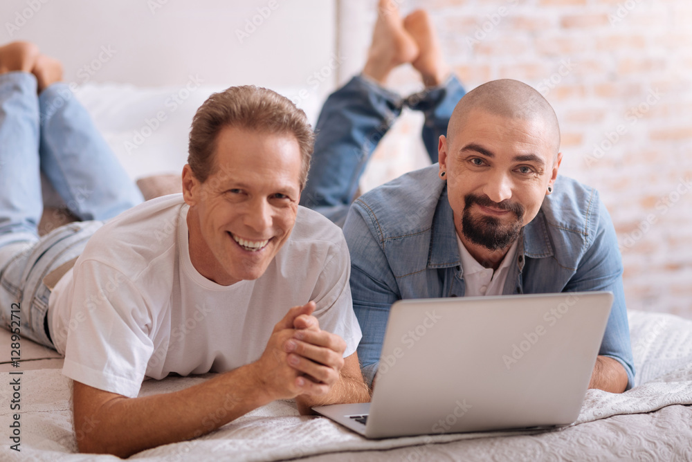 Pleasant smiling friends lying in front of the laptop Pleasant smiling friends lying in front of the laptop
