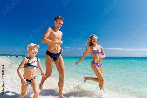 Happy family having fun running on a tropical sandy beach