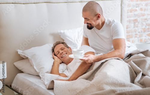 Cheerful homosexual couple having the breakfast in the bed © zinkevych