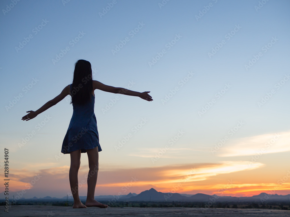 Silhouette of free woman enjoying freedom feeling happy at sunset. relaxing woman in pure happiness Silhouette of free woman enjoying freedom feeling happy at sunset. relaxing woman in pure happiness