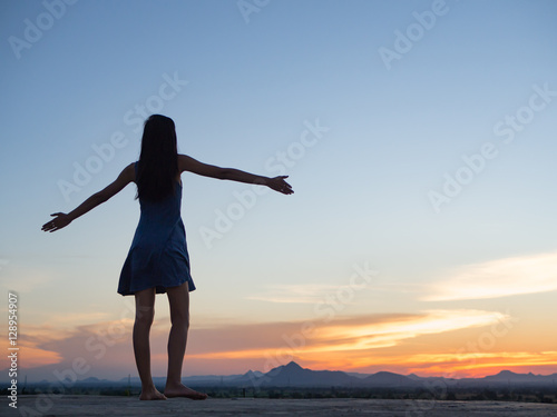 Silhouette of free woman enjoying freedom feeling happy at sunset. relaxing woman in pure happiness