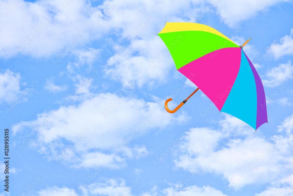 Multicolored umbrella flies in sky against of pure white clouds.Mary Poppins umbrella.