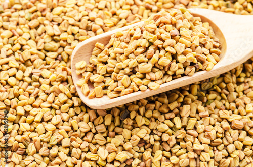 wooden scoop with fenugreek seeds fenugreek seeds. photo