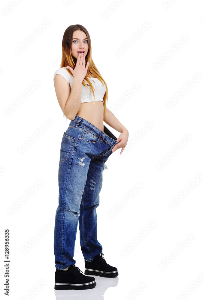 pretty girl jeans with large size enjoys a slim figure. Weight Loss. slim  girl in a loose fitting on a white background Stock Photo | Adobe Stock