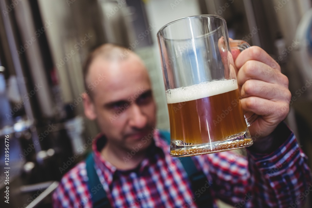 Worker examining beer in mug Worker examining beer in mug